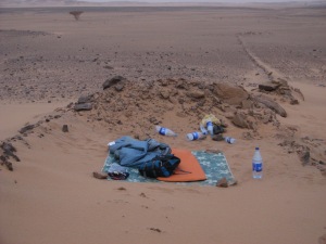 Plastic sheet, roll-up mattress and sleeping bag in that hollow in the sand; and the surrounding desert of nothingness. Lots of empty plastic bottles too.